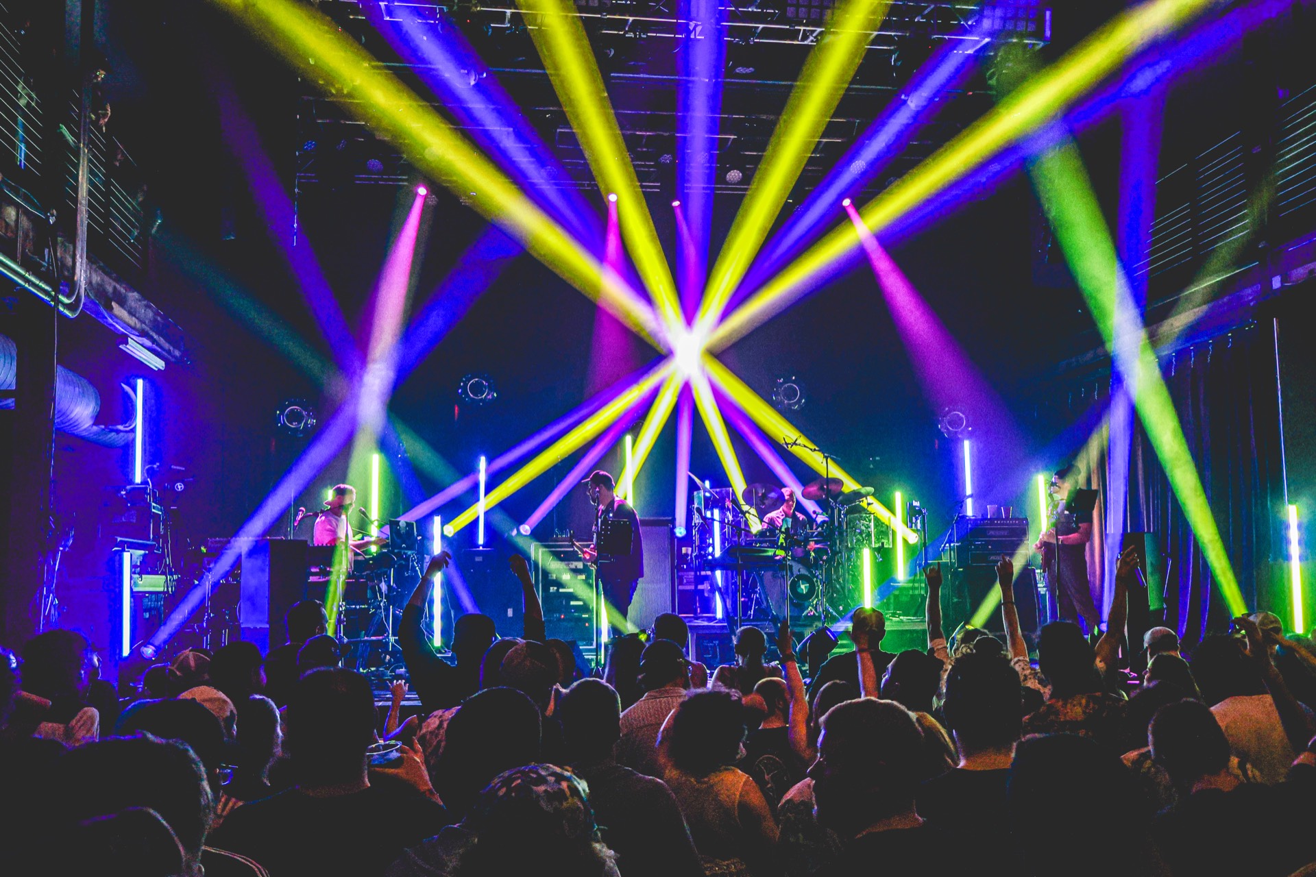 Disco Biscuits performing under multi-color starburst lighting with crowd silhouettes filling the venue