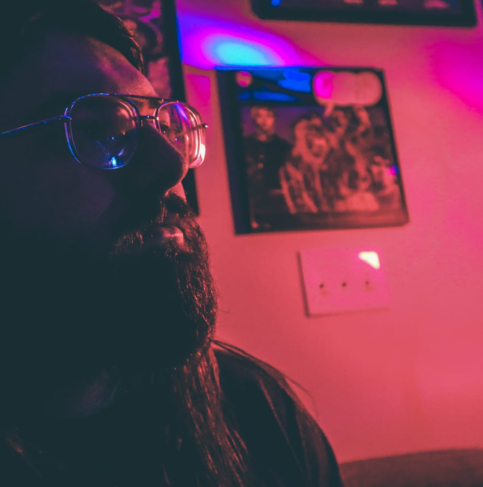 Drake Whitney, concert photographer, in profile with glasses under magenta lighting