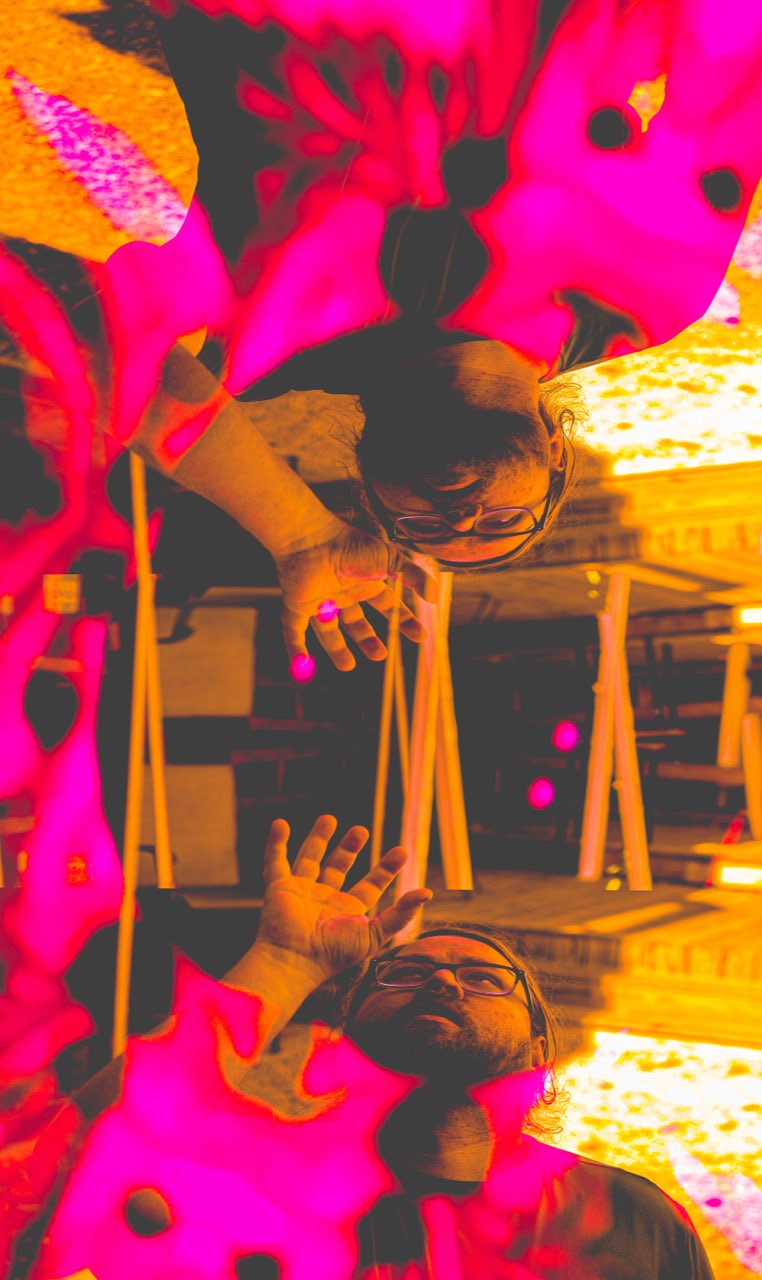 Mr. Please band member captured in a high-contrast double-exposure with mirrored figures in pink, magenta, and orange tones